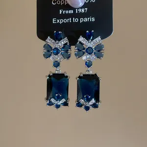 Detailed view of vintage royal style drop earrings with deep blue gemstones and zircon flowers.