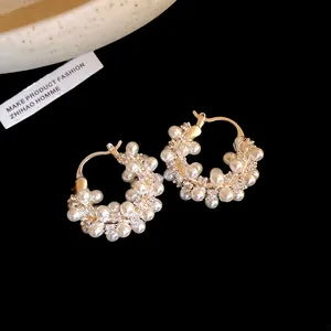 Detail of 18k gold-plated hoop earrings with pearls and shimmering zircons.