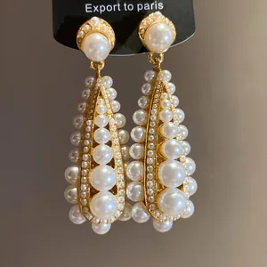 Macro view of vintage teardrop pearl dangle earrings with gold plated settings
