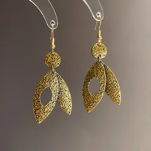 Close-up view of vintage gold leaf earrings with textured finish and hook design.