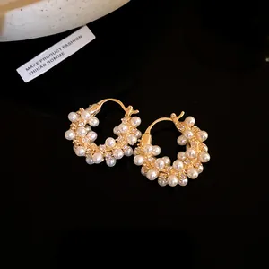 Detailed view of 18k gold plated hoop earrings with pearls and zircons on black background