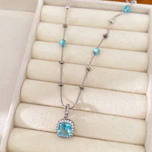Detailed macro view of a silver square blue crystal pendant necklace on velvet display
