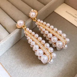 Elegant gold drop earrings featuring a cluster of white pearls inside a jewelry box