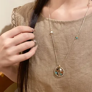 Close-up of circular openwork pendant necklace with colored stones on a model