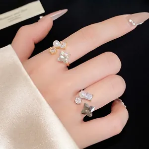 Elegante anello aperto con fiore di zircone e perla sulla mano della modella, oro e argento