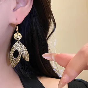 Detailed view of elegant gold leaf pendant ear hooks worn by a model in close-up