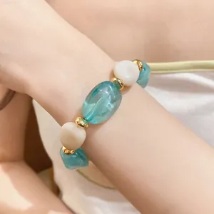 Detailansicht eines unregelmäßigen Acryl-Perlenarmbands mit blauen und weißen Perlen am Handgelenk