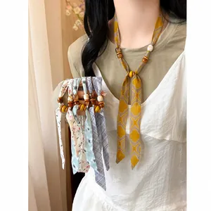 Close-up detail of floral chiffon scarf necklace with wooden beads worn by an Asian model