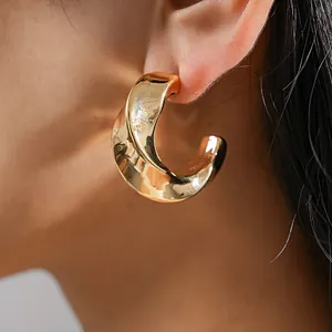 Gros plan d'une boucle d'oreille créole dorée torsadée avec un fini brillant chic