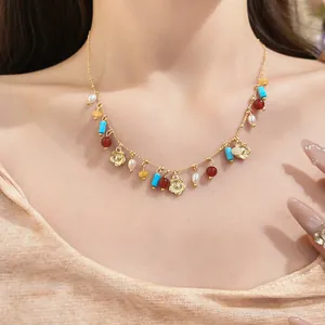 Close-up view of a beaded necklace featuring turquoise, pearls, and gold flower charms.