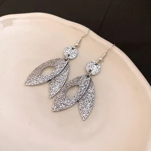 Close-up of vintage silver leaf drop earrings with detailed metal texture finish