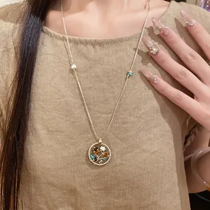 Detailed view of a round hollow pendant necklace featuring colorful stone bead accents.