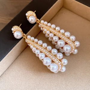 Close-up of elegant vintage drop earrings featuring multi-sized pearls in a gold setting