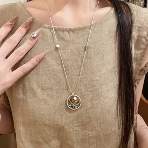 Boho style circular hollow pendant necklace with colorful stone beads worn by model