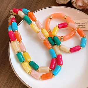 Close-up of a vibrant dopamine acrylic cylindrical bead necklace with golden spacers.