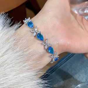 Close-up of an elegant floral bracelet with pear-cut blue zircons worn on a wrist