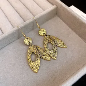 Close-up of golden leaf-shaped drop earrings with textured pattern in jewelry box