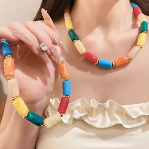 Detail of colorful dopamine acrylic necklace with marbled cylinder beads on model.