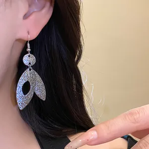 Macro detail of elegant textured silver leaf pendant drop earrings worn on model