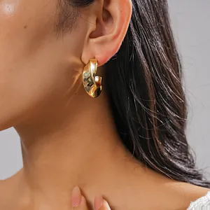 Gros plan détaillé d'une boucle d'oreille géométrique torsadée dorée sur un mannequin