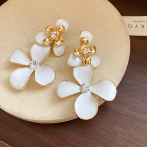Close-up of vintage white enamel flower drop earrings with sparkling rhinestones
