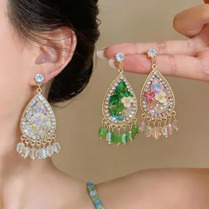Detailed view of teardrop earrings with floral resin and sparkling rhinestone tassels