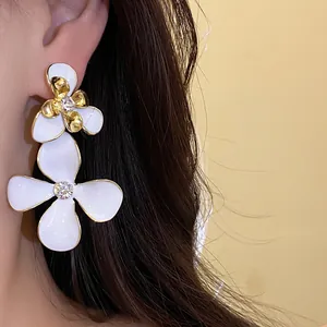Detail view of vintage white enamel flower drop earrings with sparkling rhinestones