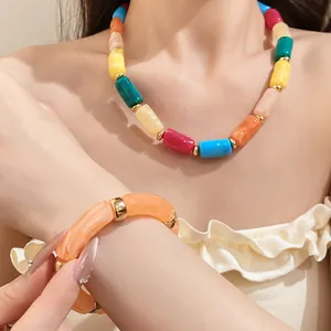 Detailed view of colorful acrylic cylindrical bead necklace and bracelet set on a model