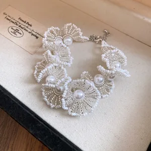 Détail d'un bracelet en perles blanches fait main de style palais français chic