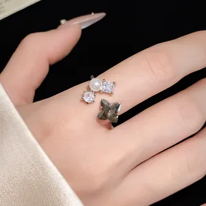 Primo piano di elegante anello aperto con perla, zircone e pietra a forma di fiore