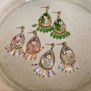 Detailed view of teardrop earrings with crystals and floral accents in three colors