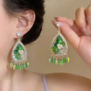 Detail view of French court style teardrop earrings with green crystals and floral accents