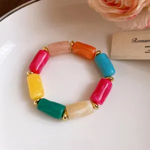 Detailed shot of multi-colored marbled acrylic barrel beads bracelet on white plate