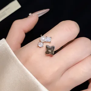 Dettaglio ravvicinato di un anello aperto argentato con design a fiore in perla e zircone.