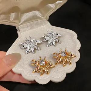 Elegant zirconia flower stud earrings in gold and silver finishes displayed on shell box