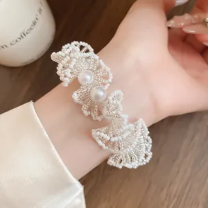 Élégant collier à fleurs en perles blanches porté comme un détail de bracelet raffiné