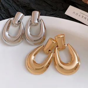 Primo piano di orecchini a cerchio a forma di U in oro e argento con finitura lucida