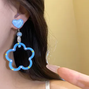 Gros plan sur des boucles d'oreilles pendantes cœur et fleur bleue style dopamine
