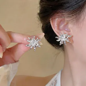 Detailed macro view of elegant silver zircon flower stud earrings on ear and hand
