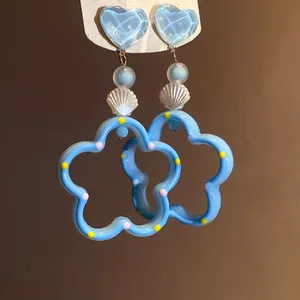 Vue détaillée des boucles d'oreilles bleu clair de style dopamine avec motifs cœur et fleur.