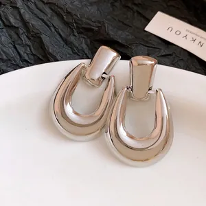 Primo piano di orecchini metallici color argento a forma di U traforati
