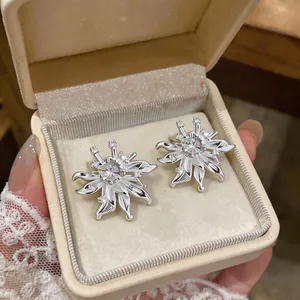 Close-up view of elegant silver-colored zircon flower stud earrings in a cream jewelry box