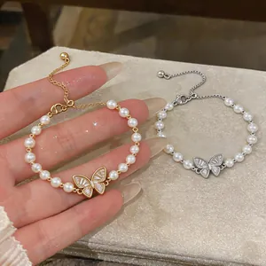 Primo piano dell'elegante ciondolo a farfalla e dei dettagli di perle del bracciale.
