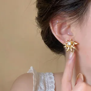 Close-up of a minimalist gold zircon flower stud earring worn on a model's ear.