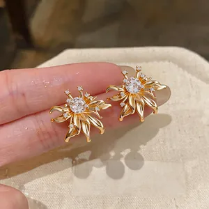 Macro detail view of elegant gold flower stud earrings with sparkling clear zircon centers.