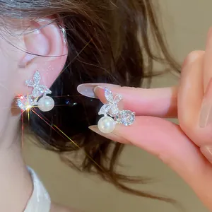 Detailed view of 18k gold plated butterfly ear clips with zircons and dangling pearls