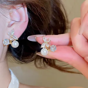 Detailed macro view of 18k gold plated butterfly ear clips with pearls and cubic zirconia