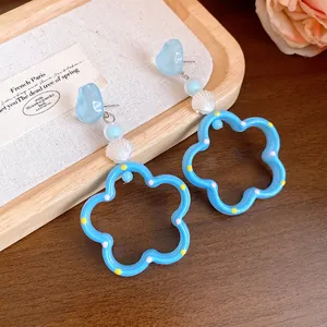 Gros plan de boucles d'oreilles fleur bleu pastel avec perles coquillage et cœur