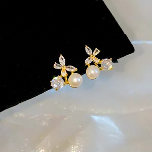 Detail of 18k gold plated butterfly ear clips with zircon and pearl accents