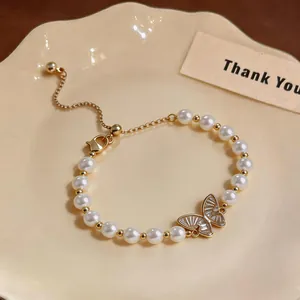 Dettaglio di un ciondolo a farfalla placcato oro 18k su un braccialetto di perle e zirconi